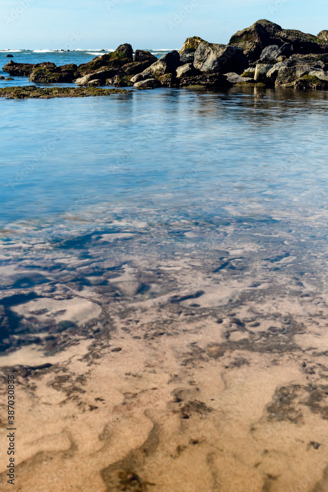 A rock formation in the beach at low tide with sky reflections A rock formation in the beach at low tide with sky reflections