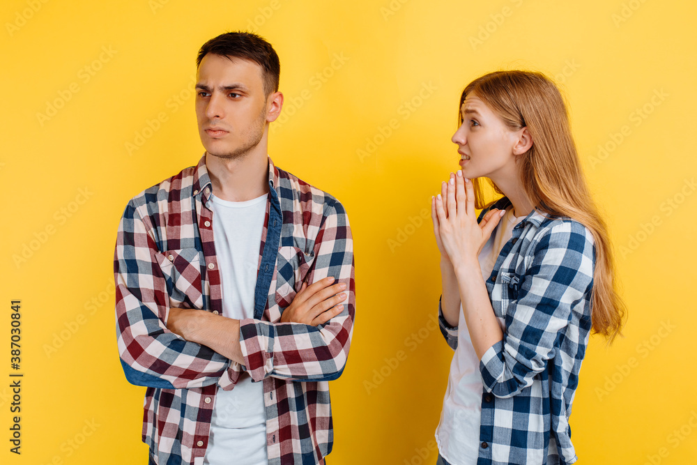 Young beautiful woman asking and begs a man on yellow background Young beautiful woman asking and begs a man on yellow background