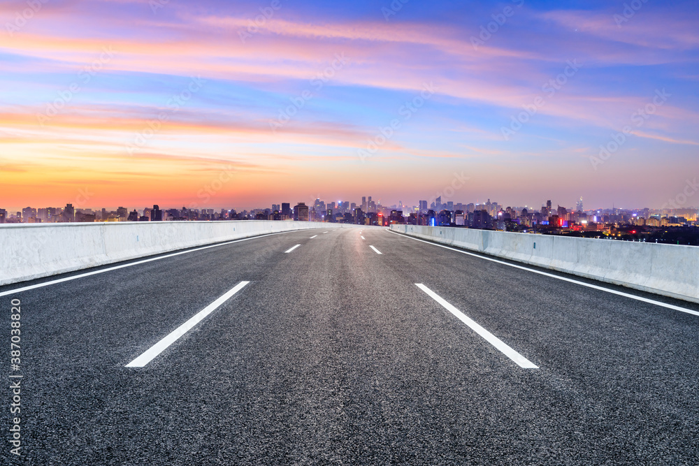 Empty asphalt road and city skyline with buildings in Hangzhou at sunrise.