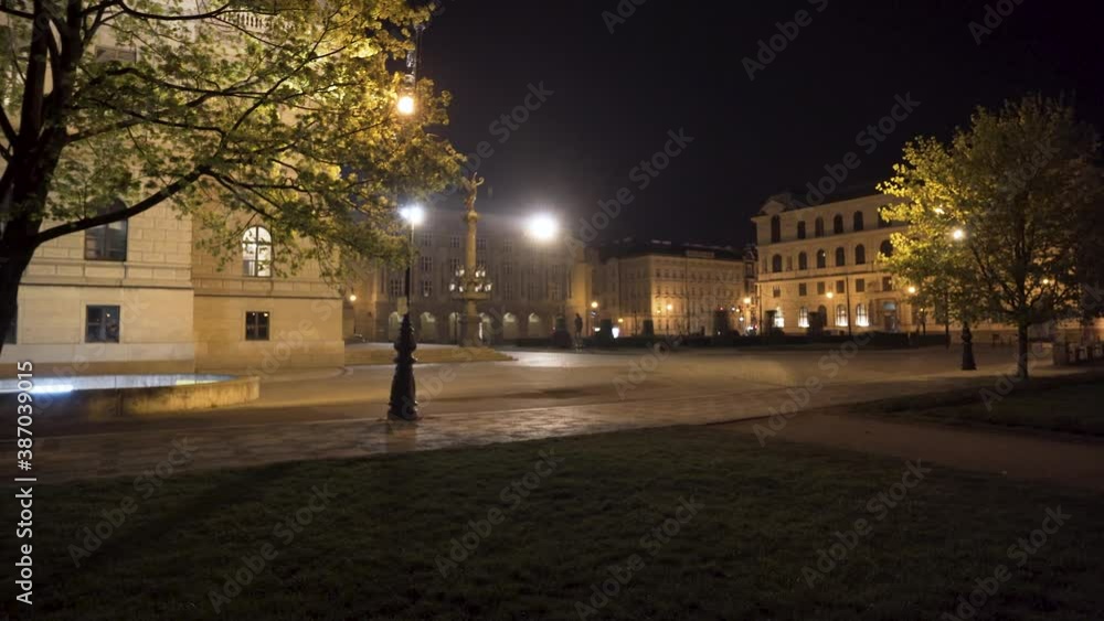 An empty historical plaza in Prague, Czechia, at night, during a Covid-19 lockdown, trees and deserted streets lit by streetlamps and the magnificent concert hall of Rudolfinum on the left,pan shot. An empty historical plaza in Prague, Czechia, at night, during a Covid-19 lockdown, trees and deserted streets lit by streetlamps and the magnificent concert hall of Rudolfinum on the left,pan shot.