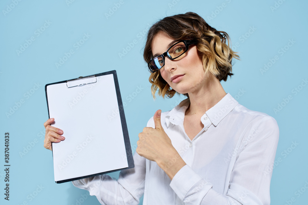 Business woman with documents in a folder on a blue background and in a light shirt glasses on her face Business woman with documents in a folder on a blue background and in a light shirt glasses on her face