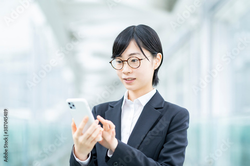 Free Download スマートフォンを操作するスーツ姿の若い女性 - GFXLoad