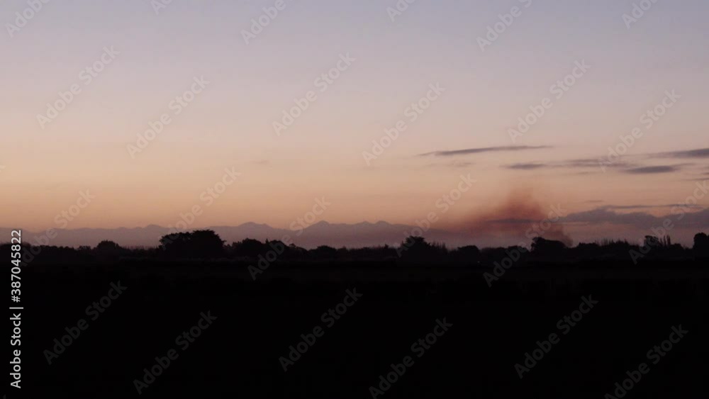 Sunset in the field in New Zealand with smoke comming out of family cottage. Sunset in the field in New Zealand with smoke comming out of family cottage.