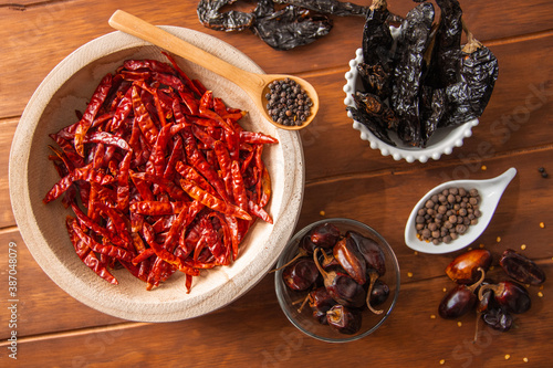 Tazón de madera con chiles secos y especias en detalle en mesa de madera