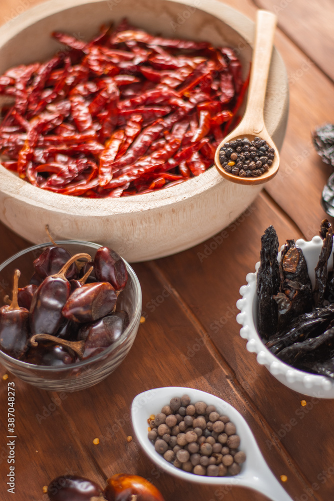 Tazón de madera con chiles secos y especias en detalle en mesa de madera Tazón de madera con chiles secos y especias en detalle en mesa de madera