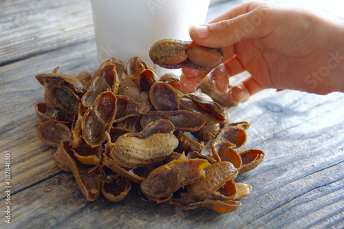 Hand holding a boiled peanut over a table with empty peanut shells