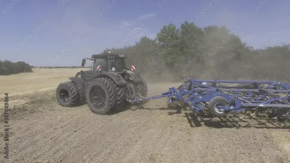 Close up aerial shot of a tractor with a hoeing attachment working the field