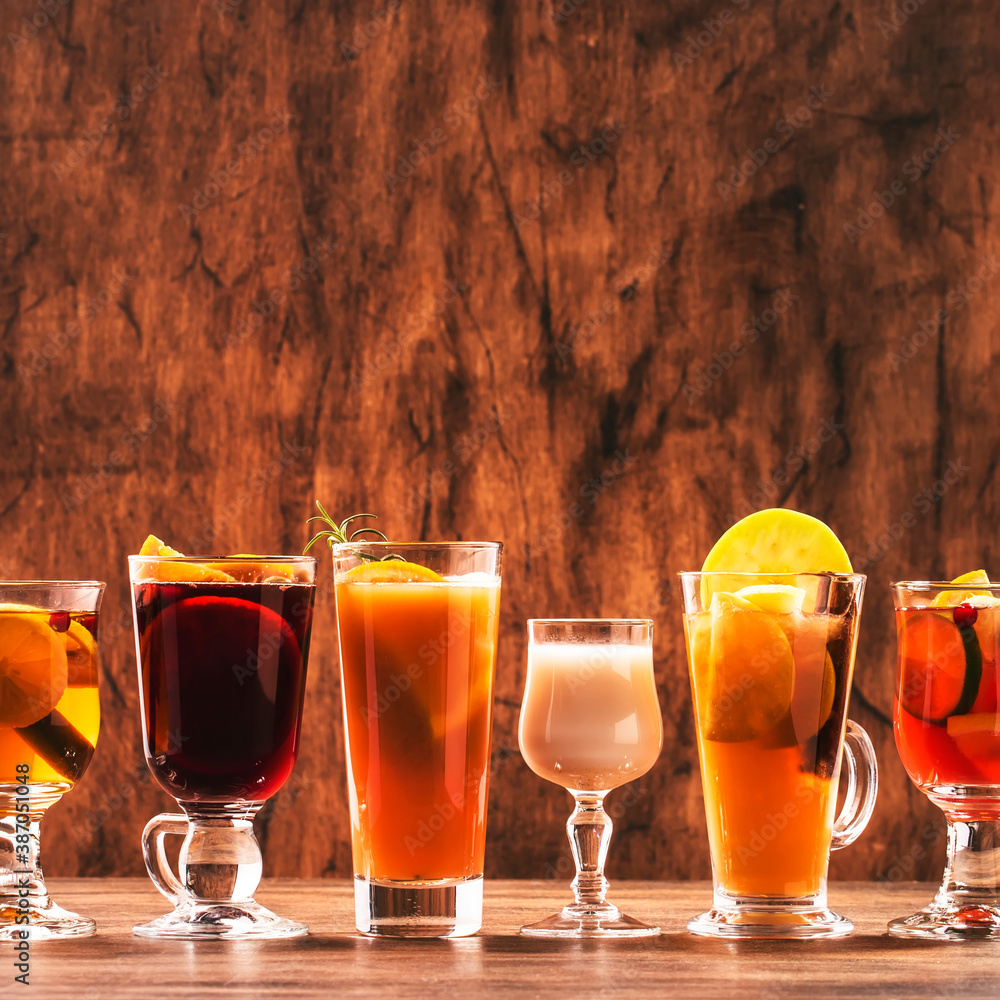 Selection of autumn or winter alcoholic hot drinks and cocktails - mulled wine, glogg, grog, eggnog, warm ginger ale, hot buttered rum, punch, mulled apple cider on wood background, copy space - obrazy, fototapety, plakaty 