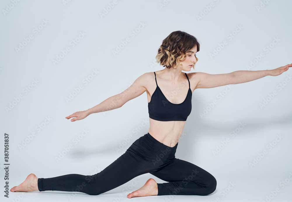 A woman in black jeans sits on the floor on one leg and gestures with her hands A woman in black jeans sits on the floor on one leg and gestures with her hands