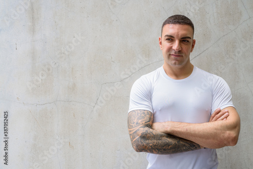 Portrait of handsome man with tattoos thinking with arms crossed © Ranta Images