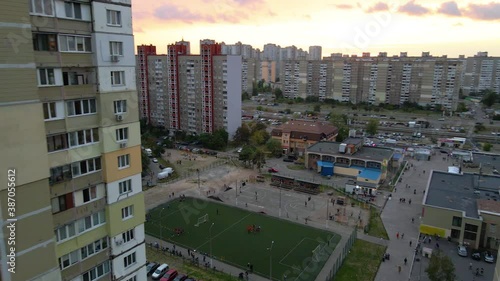 Aerial view between old soviet made apartment buildings, revealing a soccer field, in a indigent slum neighborhood of Kyiv, during sunset, in Kiev, Ukraine - rising, drone shot