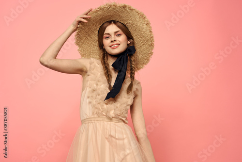 Fashionable woman in dress and hat with black ribbon on pink background cropped view of model emotions fun
