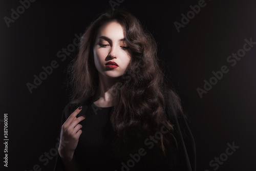 Vintage portrait with harsh light of a beautiful, slim brunette woman with bright makeup and wavy hair