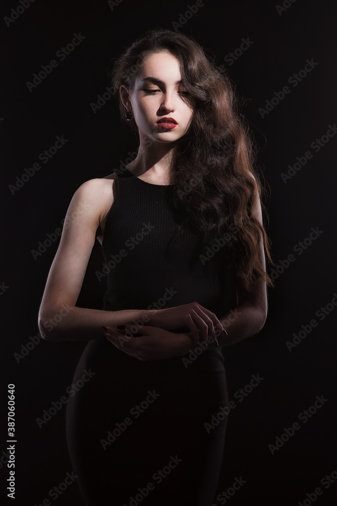 Naklejka premium Vintage portrait with harsh light of a beautiful, slim brunette woman with bright makeup and wavy hair
