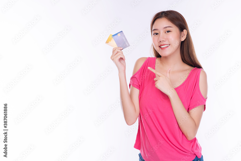 Cheerful young woman wearing casual clothes while holding and pointing credit card mockup looking at camera over isolated white background. Payment purchase and financial concept. Cheerful young woman wearing casual clothes while holding and pointing credit card mockup looking at camera over isolated white background. Payment purchase and financial concept.