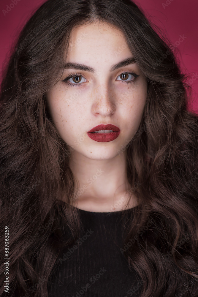 Portrait of a young brunette with lush wavy hair and beautiful highlights in the eyes Portrait of a young brunette with lush wavy hair and beautiful highlights in the eyes