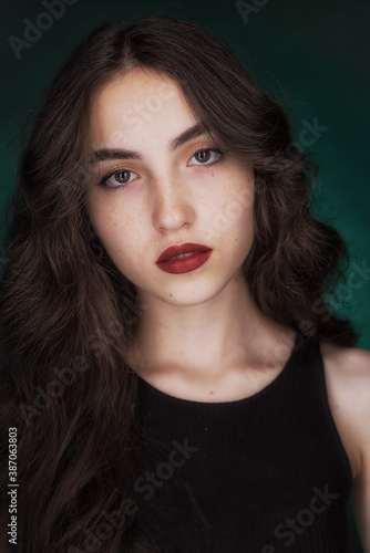 Portrait of a young brunette with lush wavy hair and beautiful highlights in the eyes