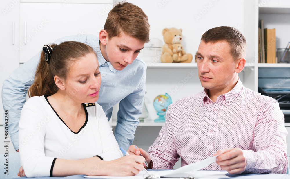 Obraz premium Middle-aged mother and son signing beneficial financial agreement at home