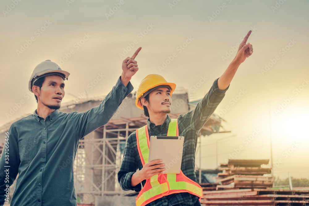Two Engineer discussing on site building construction holding blueprint Two Engineer discussing on site building construction holding blueprint
