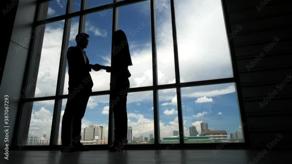 Silhouettes of two business people shaking hands in the office. Silhouettes of two business people shaking hands in the office.