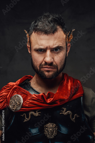 Fotografie Serious and bearded roman emperor dressed in dark armour and red cloak