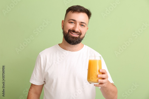 Man with orange juice on color background