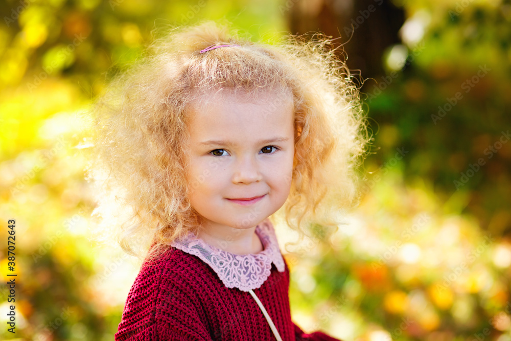 Adorable little girl curly blonde is having fun on a beautiful autumn day. Happy child playing in autumn Park. Autumn events for children. Adorable little girl curly blonde is having fun on a beautiful autumn day. Happy child playing in autumn Park. Autumn events for children.