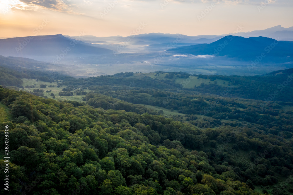 Early morning in the mountains. Morning sun and haze in the valley against the background of mountains. Green fields and meadows. Adygea, Russia Early morning in the mountains. Morning sun and haze in the valley against the background of mountains. Green fields and meadows. Adygea, Russia