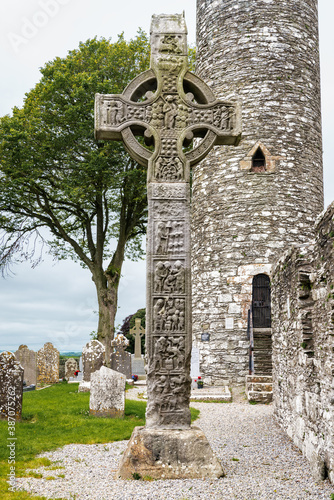 Drogheda, Ireland - July 15, 2020: View of East face of West high celtic cross and round tower at early Christian monastic settlement Monasterboice founded in 5th century. photo