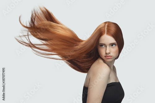 Fototapeta Beautiful model with long smooth, flying red hair isolated on white studio background
