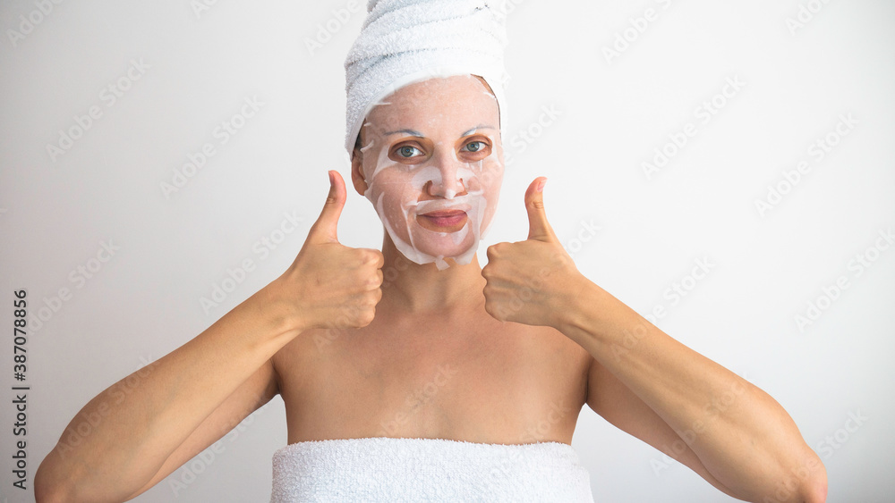 Woman in towels with cosmetic mask gives a thumbs up. Negative space or copy space for text. Woman in towels with cosmetic mask gives a thumbs up. Negative space or copy space for text.