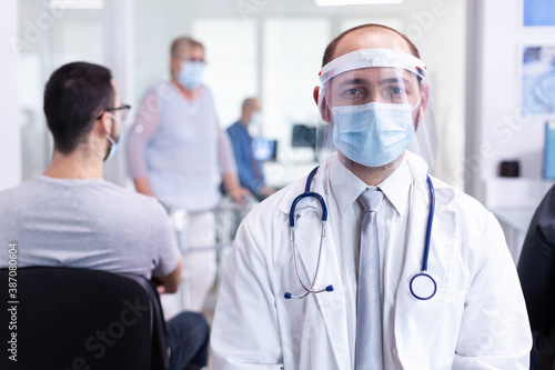 Portrait of doctor with face mask as safety precaution against coronavirus in hospital waiting area. Doctor in hospital hallway with medical mask protection epidemic against covid-19. Medical