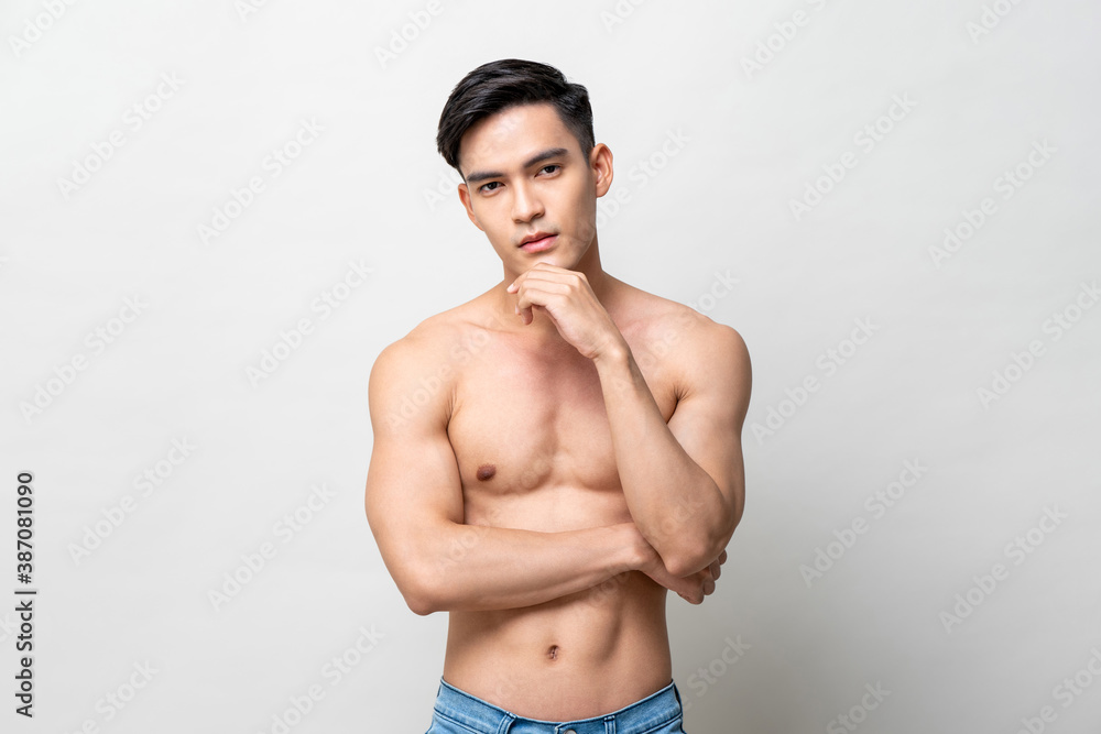 Shirtless handsome Asian man posing with hand touching chin on isolated gray background