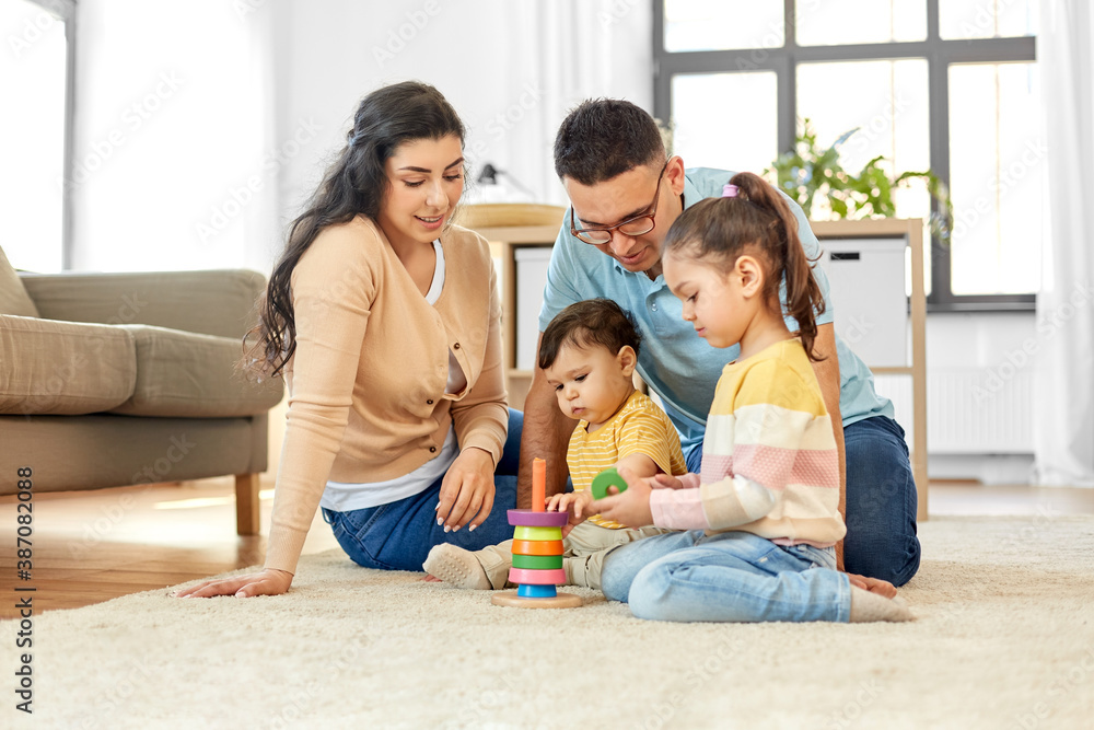 family and people concept - happy mother, father, little daughter and baby son playing with pyramid toy at home family and people concept - happy mother, father, little daughter and baby son playing with pyramid toy at home