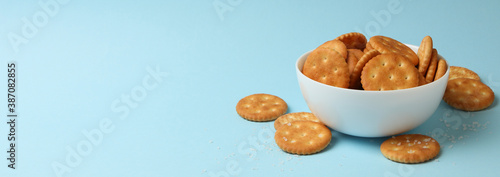Bowl with tasty cracker biscuits on blue background