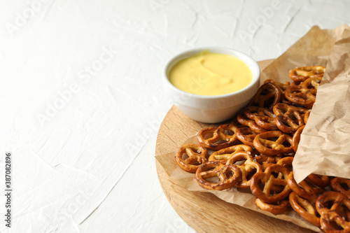 Tasty cracker pretzels and cheese sauce on white background
