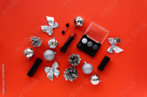 Christmas or new year flat lay of makeup products and decorations. Eyeshadow palette and lipstick on a red background photo