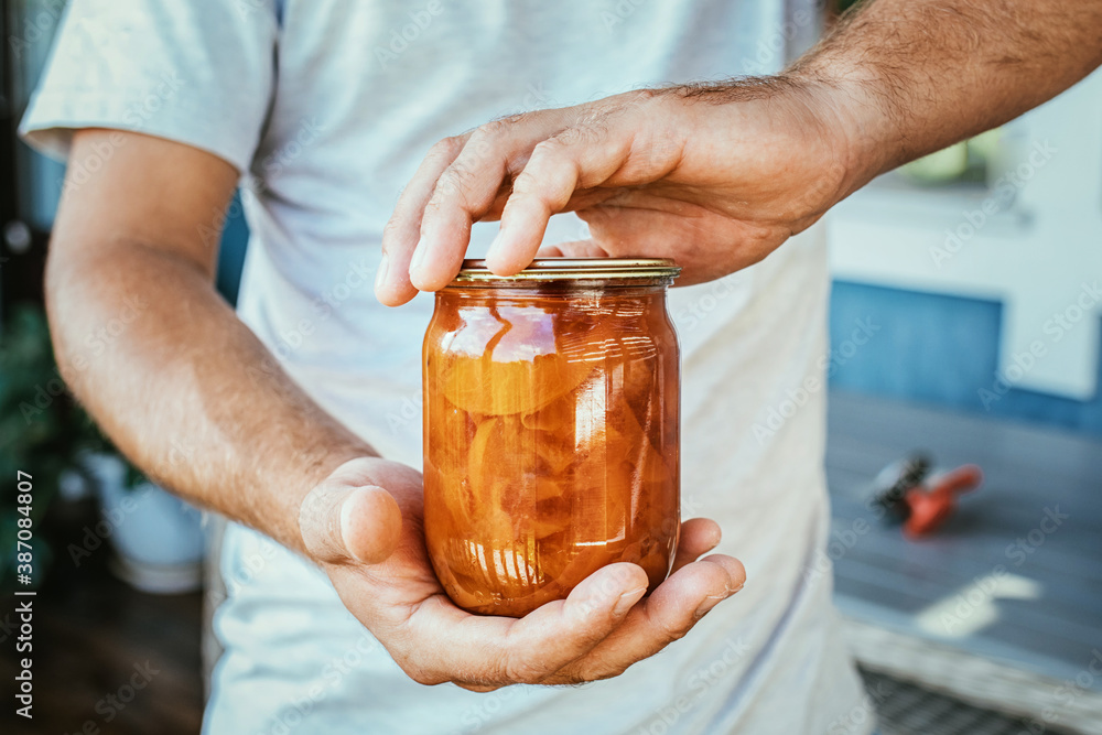 jar of peach jam in men's hands, canning jar of peach jam in men's hands, canning