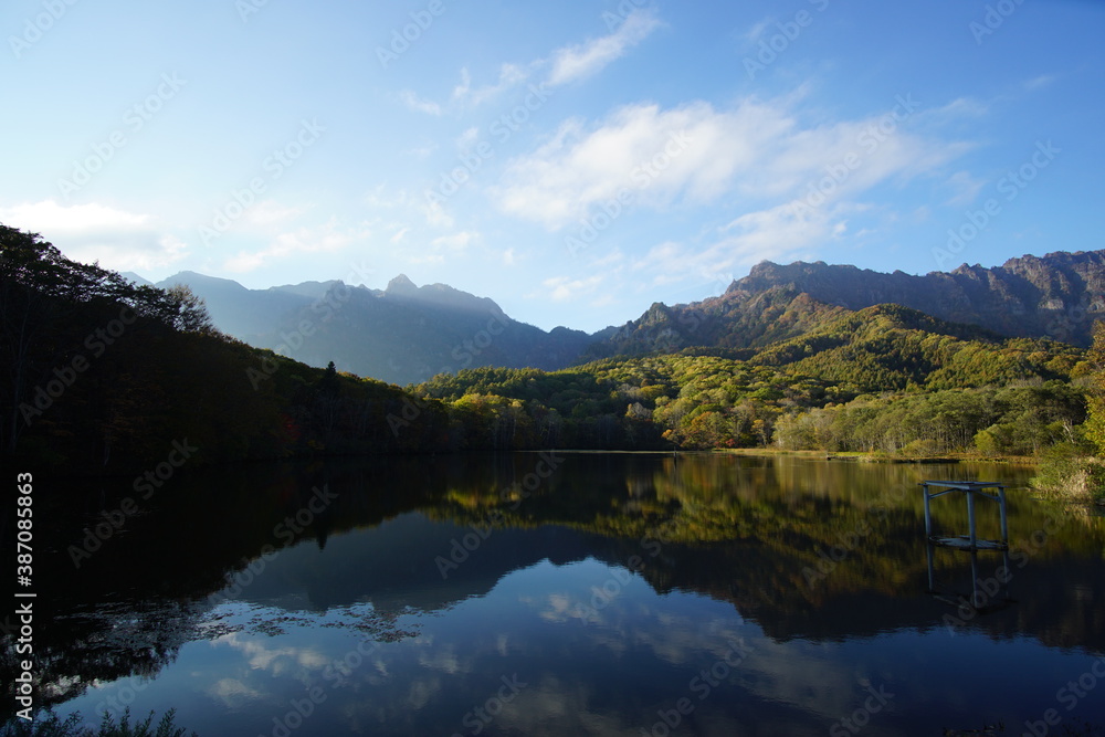 A pond that reflects trees and mountains like a mirror. At dusk. Beautiful scenery of Japan.