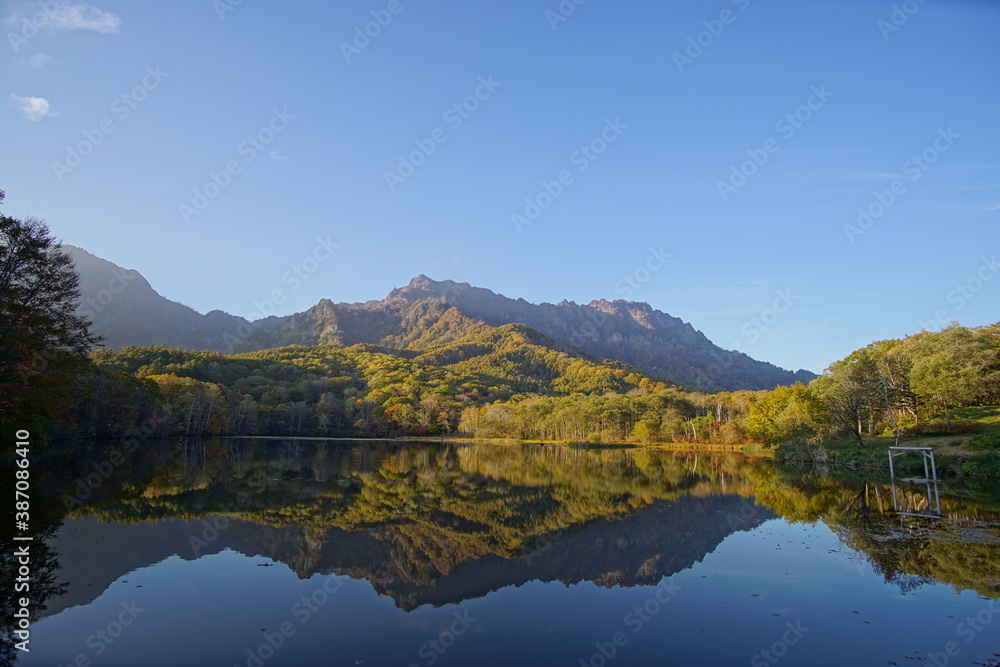 A pond that reflects trees and mountains like a mirror. At dusk. Beautiful scenery of Japan.