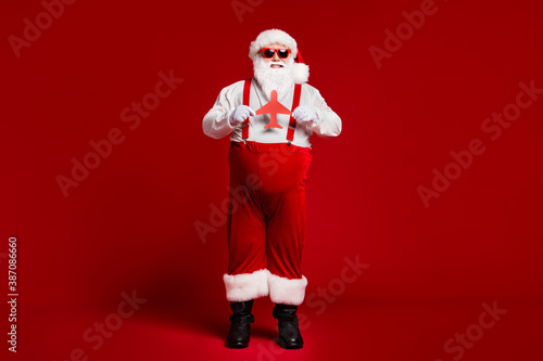 Full length body size view of his he attractive cheerful cheery glad fat Santa holding in hands paper plane figure isolated bright vivid shine vibrant red burgundy maroon color background