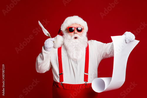 Portrait of his he attractive amazed stunned funny fat white-haired Santa writing wish present list North Pole isolated bright vivid shine vibrant red burgundy maroon color background photo