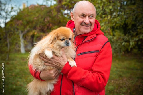 Senior man with a red little dog outdoor, man retired, lifestyle of older people