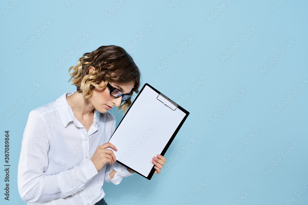 Business woman with documents in a folder on a blue background and in a light shirt glasses on her face Business woman with documents in a folder on a blue background and in a light shirt glasses on her face