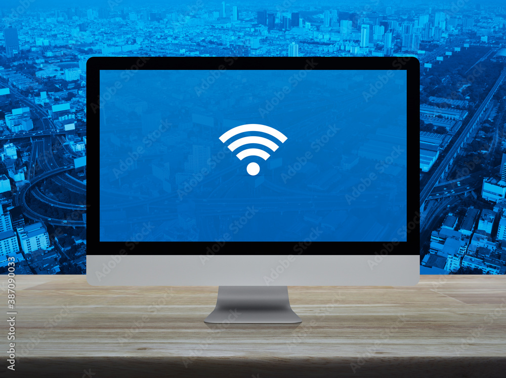 Wi-fi flat icon on desktop modern computer monitor screen on wooden table over city tower, street, expressway and skyscraper, Technology internet online concept Wi-fi flat icon on desktop modern computer monitor screen on wooden table over city tower, street, expressway and skyscraper, Technology internet online concept