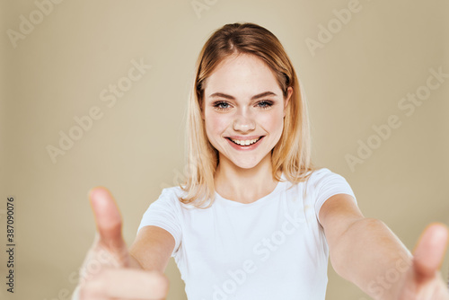 Wallpaper Mural Cheerful blonde woman in a white T-shirt gestures with her hand emotions beige background Torontodigital.ca