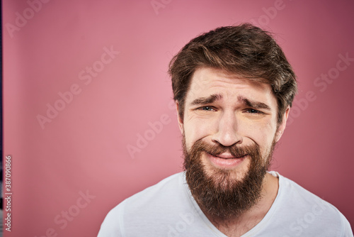 bearded man in white t-shirt emotions displeased facial expression studio pink background © SHOTPRIME STUDIO