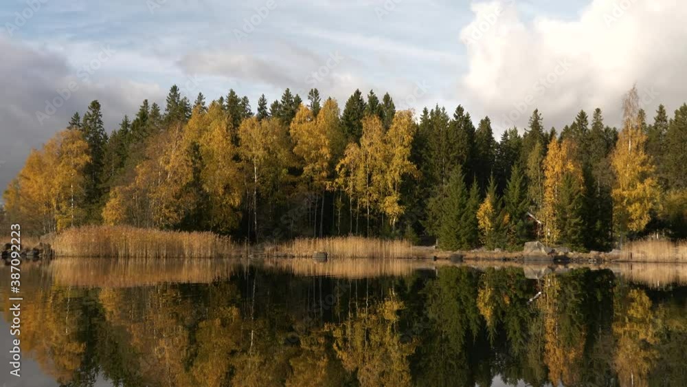 View from water of still Nordic lake reflecting colorful autumn trees View from water of still Nordic lake reflecting colorful autumn trees