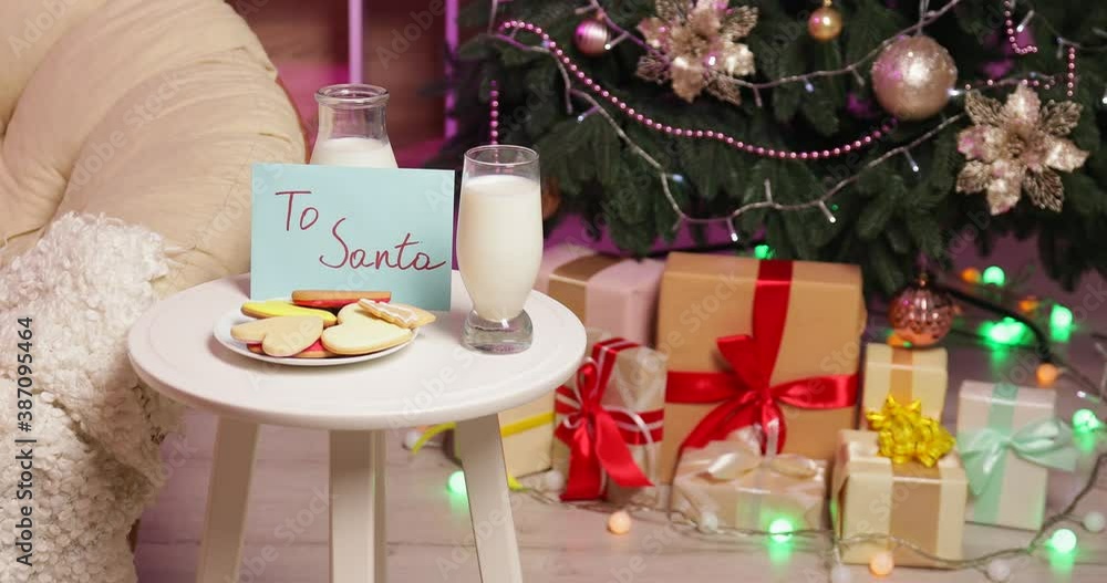Woman putting cookies and milk on table with letter to Santa at home Woman putting cookies and milk on table with letter to Santa at home