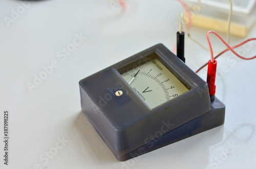 An old black analog voltmeter with wires  , white background photo